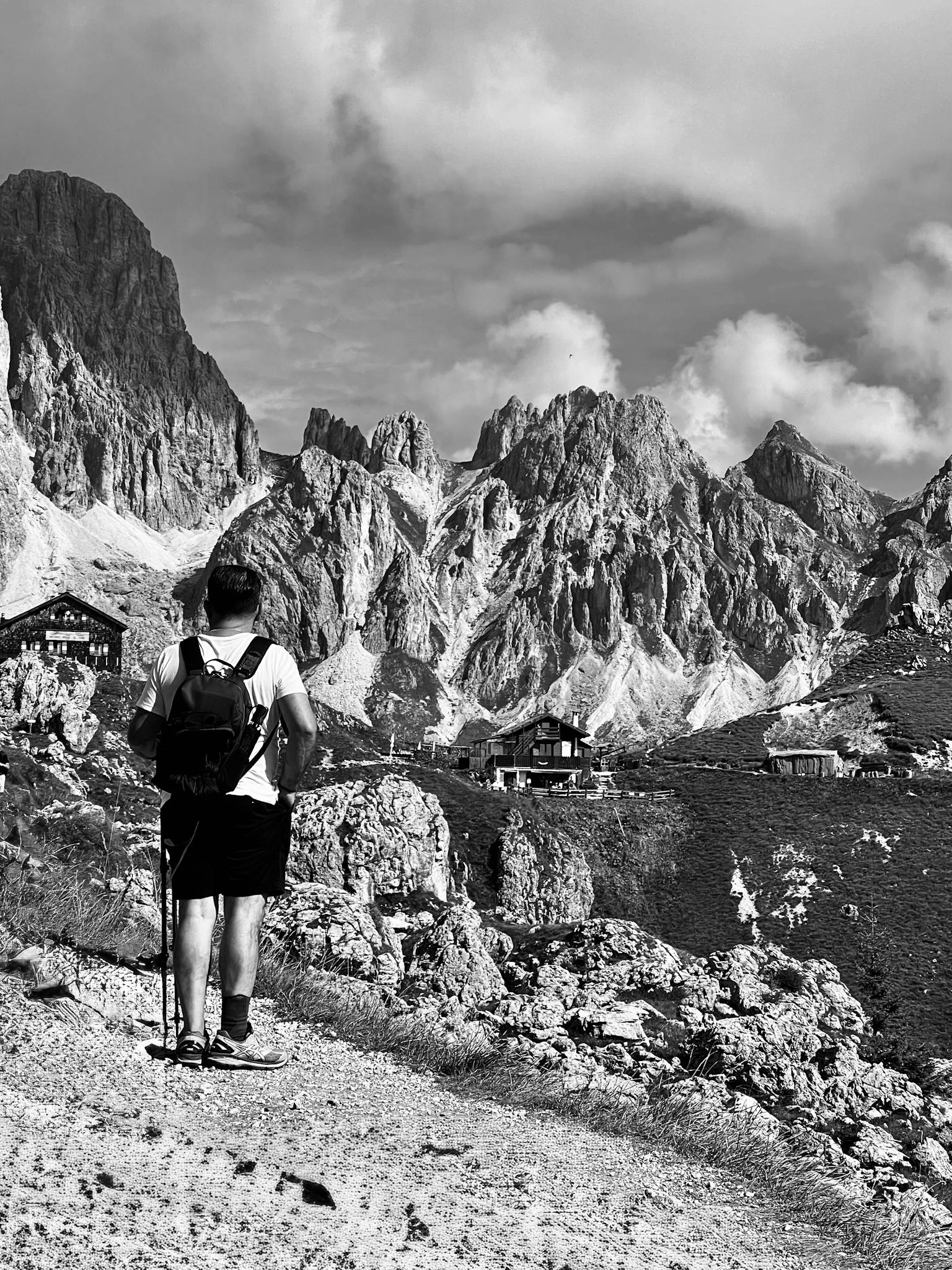 Man hiking in mountainous terrain, showcasing rugged peaks in black and white.